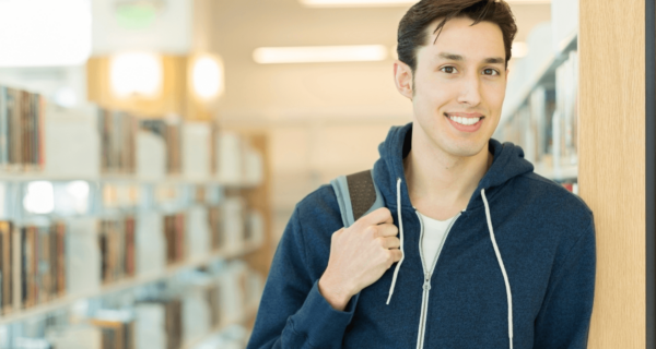 Man holding backpack and smiling in a library