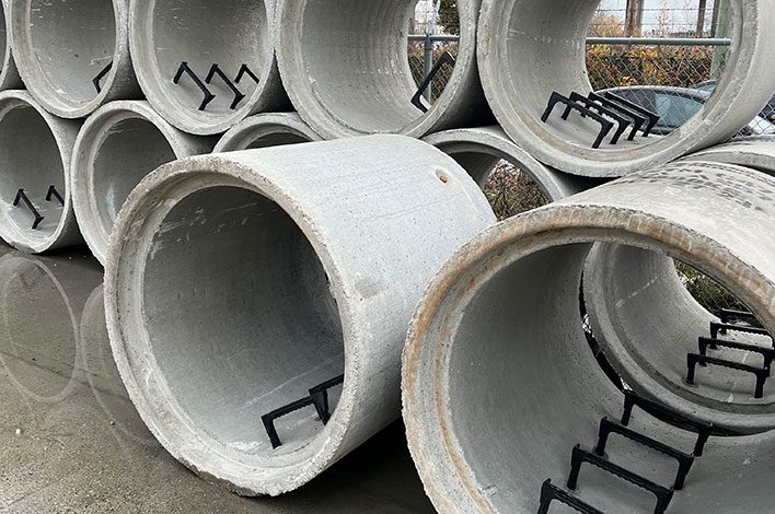 Precast concrete products sit in a manufacturing plant yard.