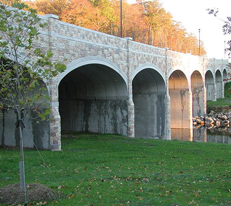 A multi-arched precast concrete bridge spans a river.