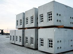 Utility vaults are stacked in a precast concrete plant yard.