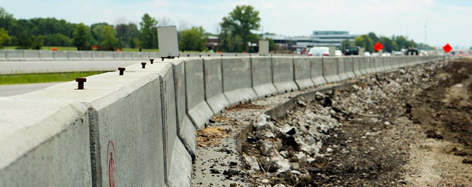 Highway barriers line a construction area along a busy roadway.