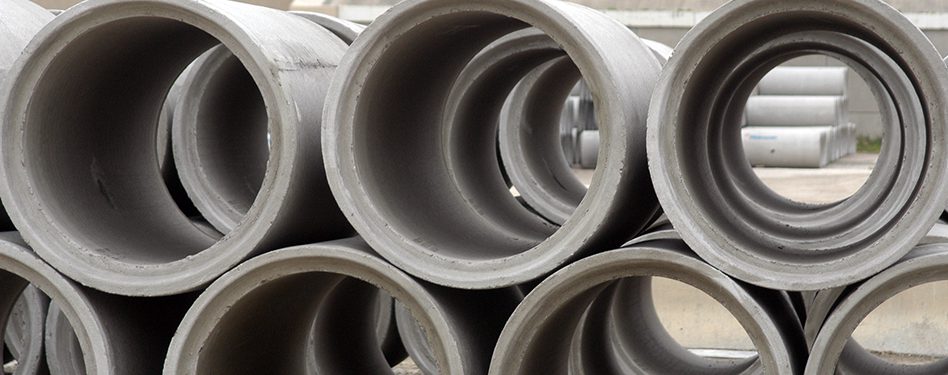 Precast concrete pipes are stacked at a manufacturing facility.