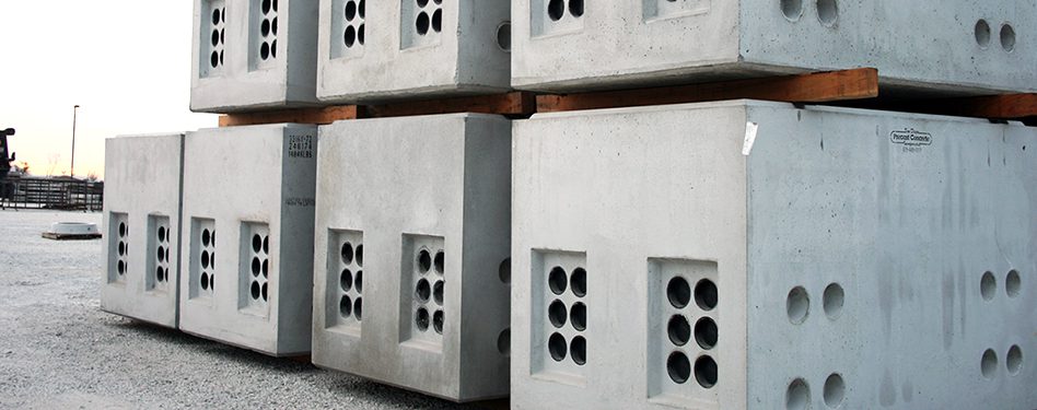 Utility vaults are stacked in a precast concrete yard.