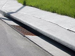 A precast curb inlet is installed along a roadway.