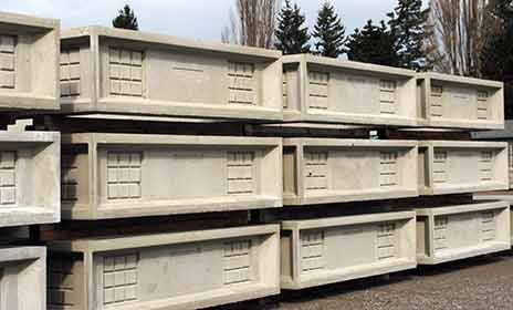 Custom precast concrete items are stacked in a yard.