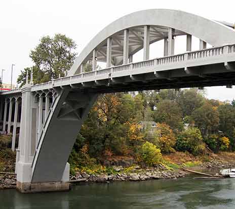 A precast concrete bridge with a beautiful arch spans a river.