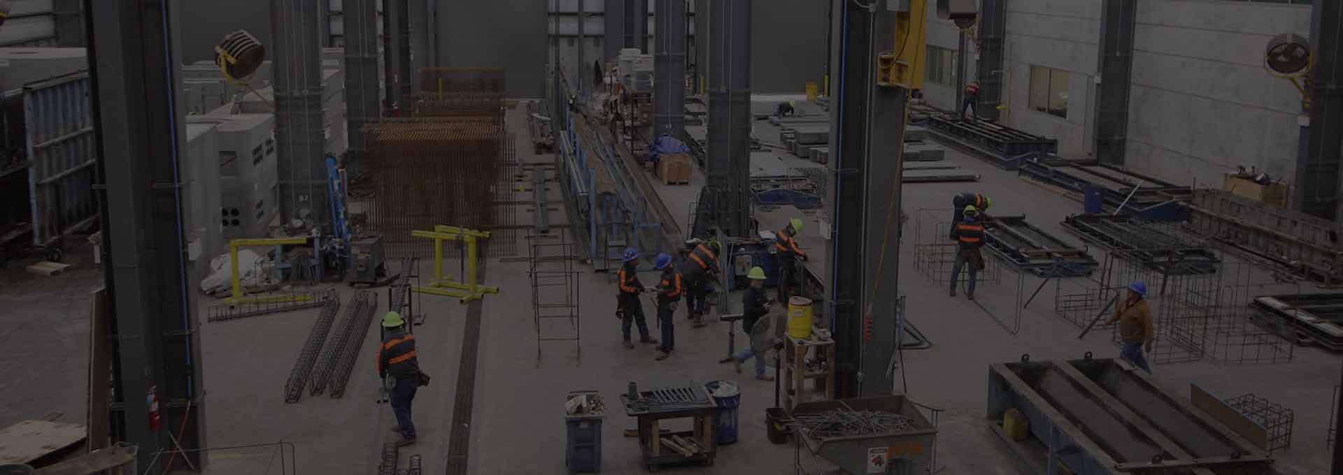 Workers perform various jobs on the floor of a precast concrete plant.