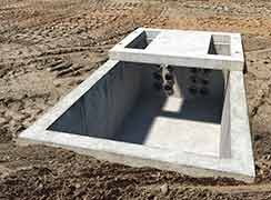 A rectangular concrete utility vault is installed in the ground.
