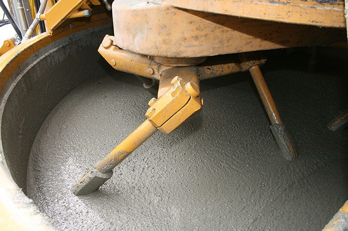 A mixer's paddles stir concrete.