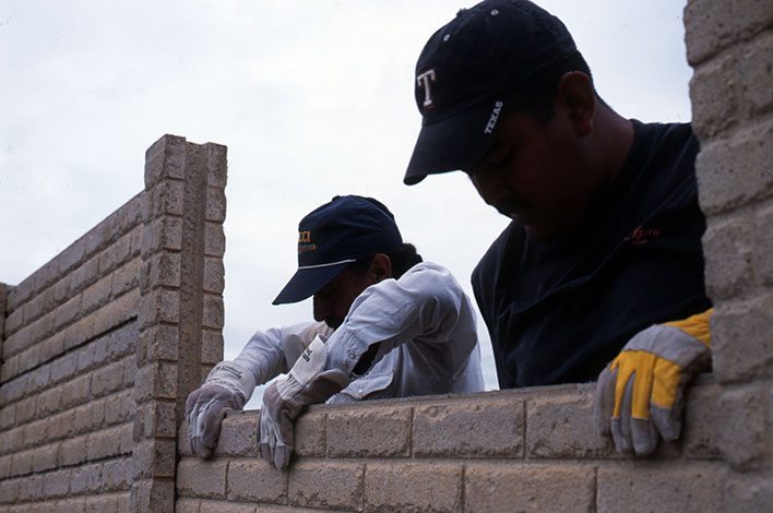 Two workers build a wall.