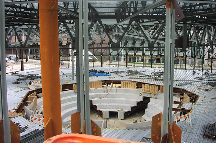 Several sets of wide steps are positioned in a circle in a building under construction.