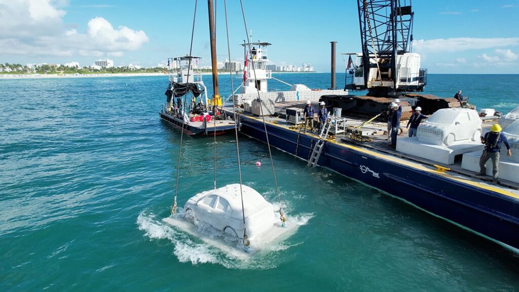 Concrete car sculpture being lowered into the water